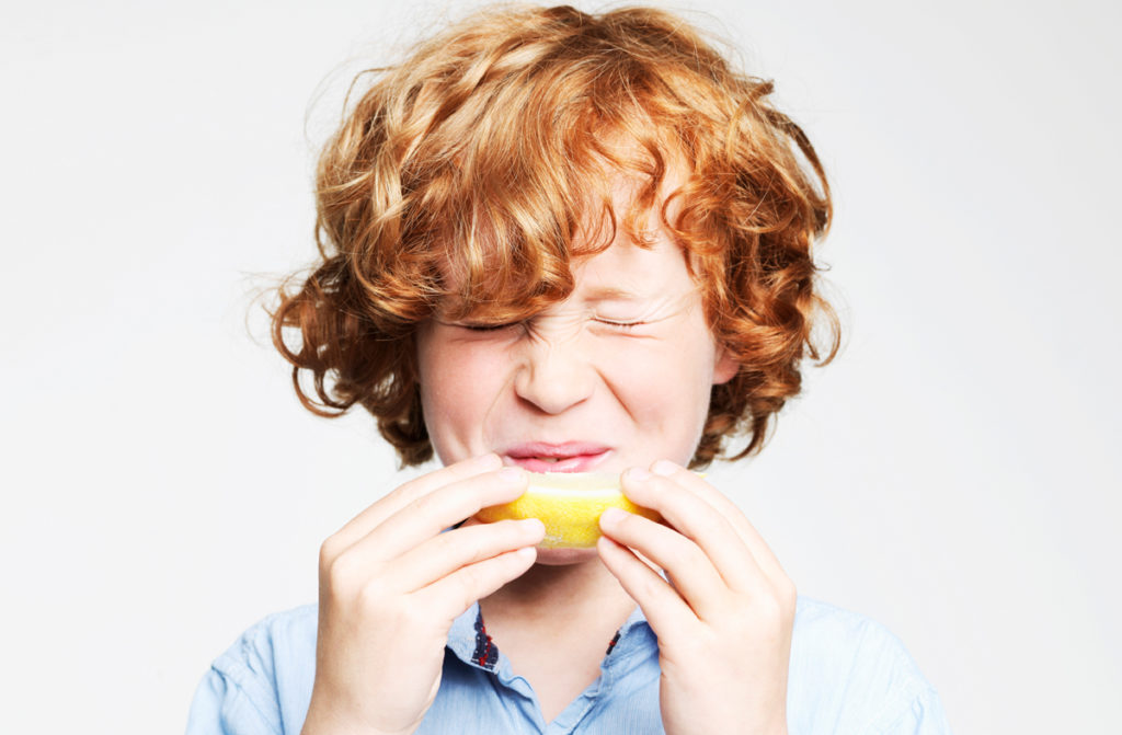 young boy tasting sour lemon